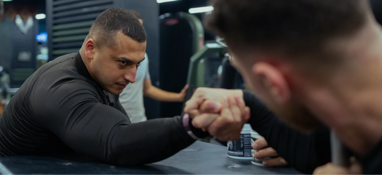 Two athletes arm wrestling during a Skeleton Nutrition gym event