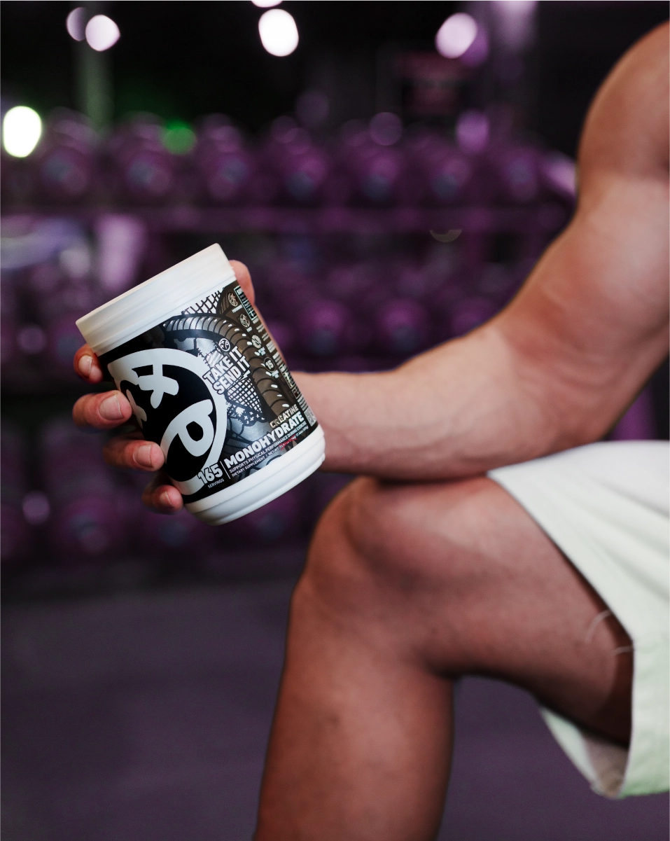 Athlete holding SKELETON® Creatine Monohydrate supplement in gym before workout