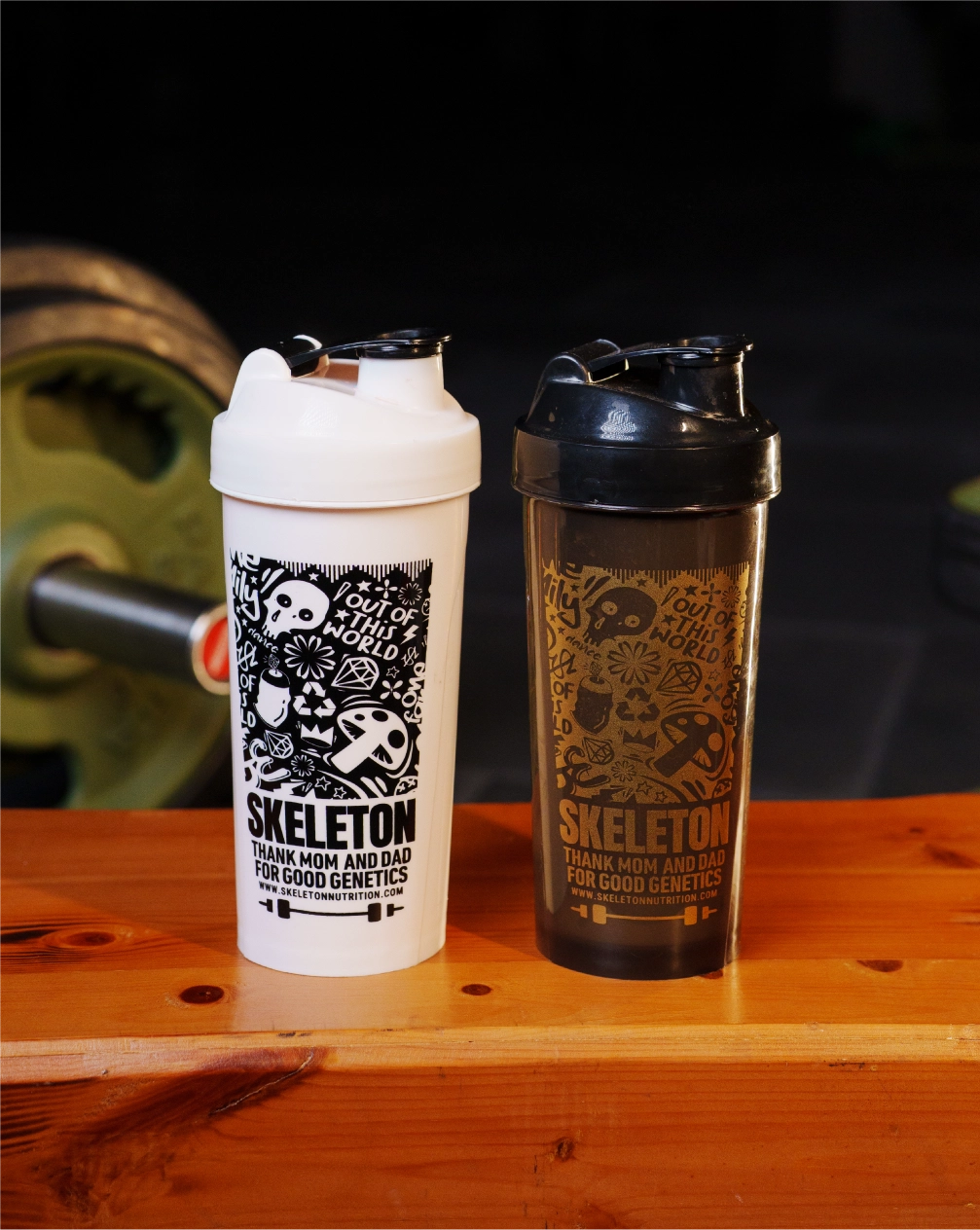 Two skeleton tattoo shaker bottles with skeleton-themed designs on a wooden surface.