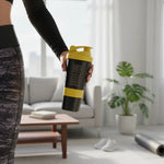 Skeleton Nutrition yellow and black smart shaker bottle held by an athlete in a bright modern living room